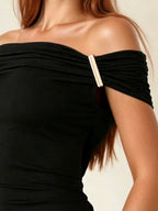 Black off-shoulder top with a gold accent on a neutral background