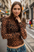 Woman wearing a leopard print top and denim jeans on a city street.