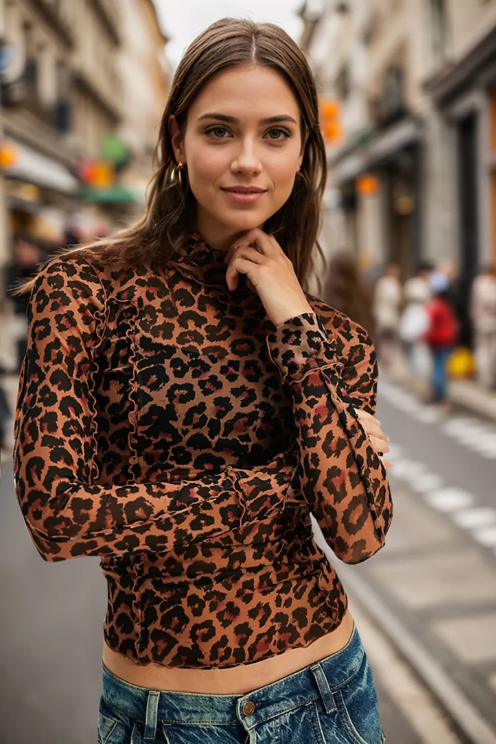 Woman wearing a leopard print top and denim jeans on a city street.