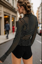 Woman wearing a black polka dot blouse and black shorts on a city street.