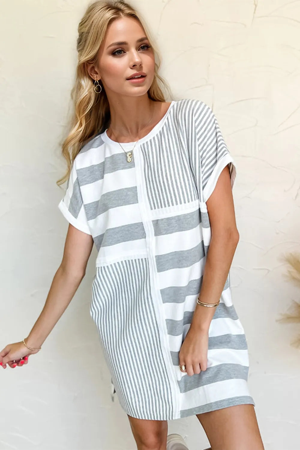 Woman wearing a gray and white striped dress against a plain background