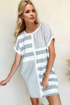 Woman wearing a gray and white striped dress against a plain background