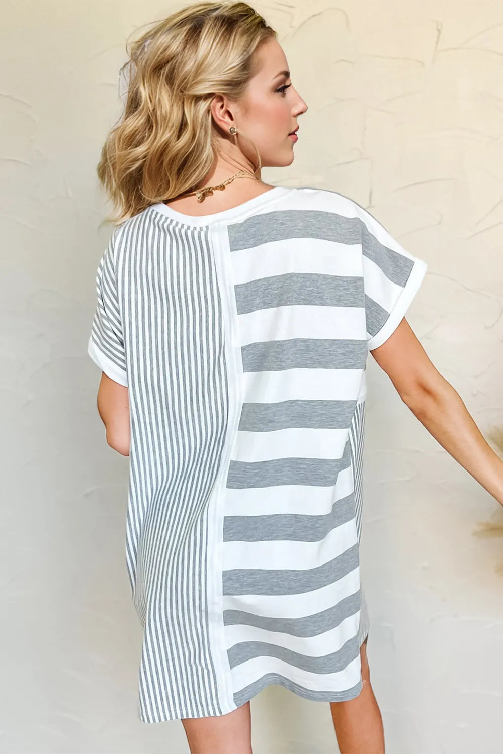 Woman wearing a gray and white striped dress against a plain background