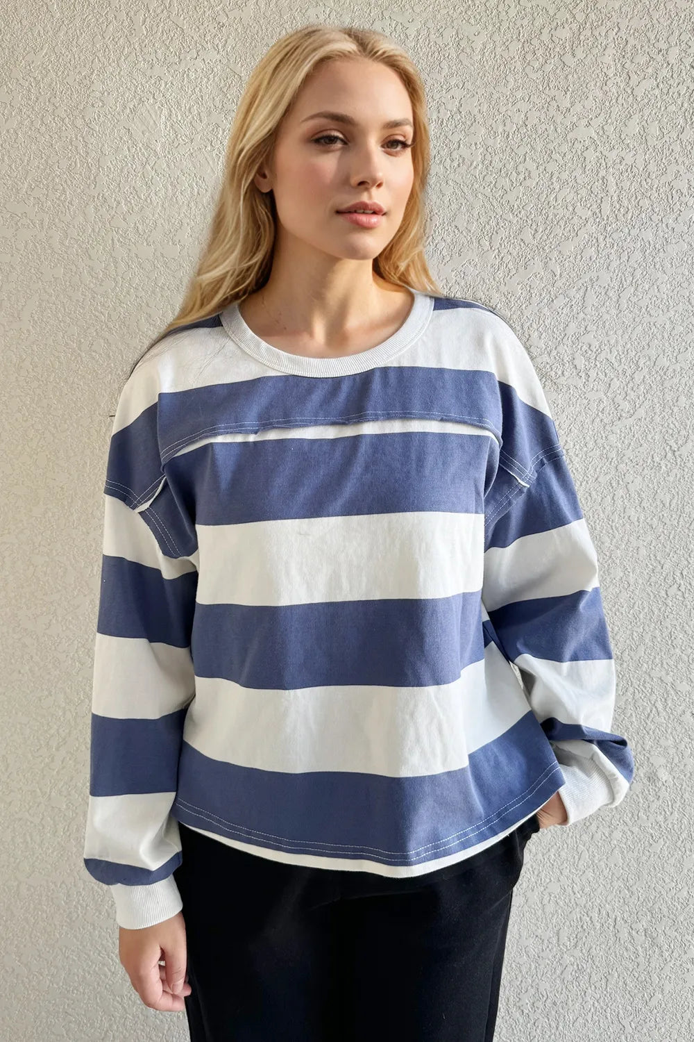 Woman wearing a blue and white striped sweater against a plain background