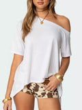 Woman wearing a white off-shoulder top and patterned shorts on a plain background