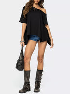Woman wearing a black off-shoulder top, denim shorts, and black knee-high boots on a white background