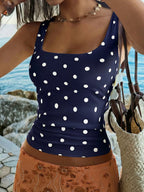 Woman wearing a navy blue tank top with white polka dots by the water.