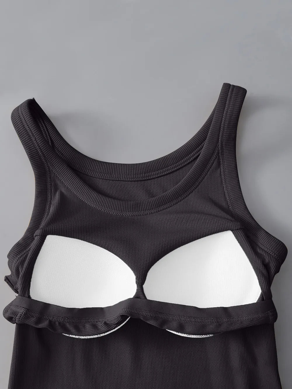 Black tank top with white bra cups on a gray background
