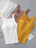 Three tank tops in white, brown, and yellow on a gray background