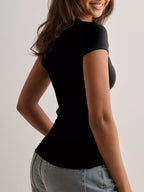 Woman wearing a black top and blue jeans against a plain background