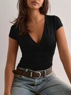 Woman wearing a black top and blue jeans against a plain background