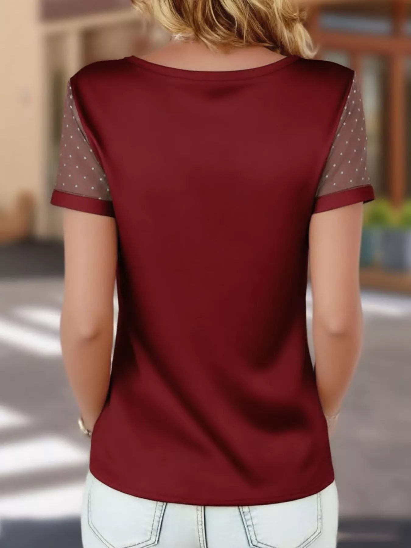 Red blouse with sheer sleeves worn by a person, blurred background