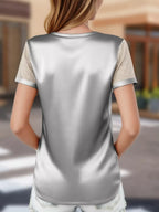Person wearing a silver and beige top with a blurred background