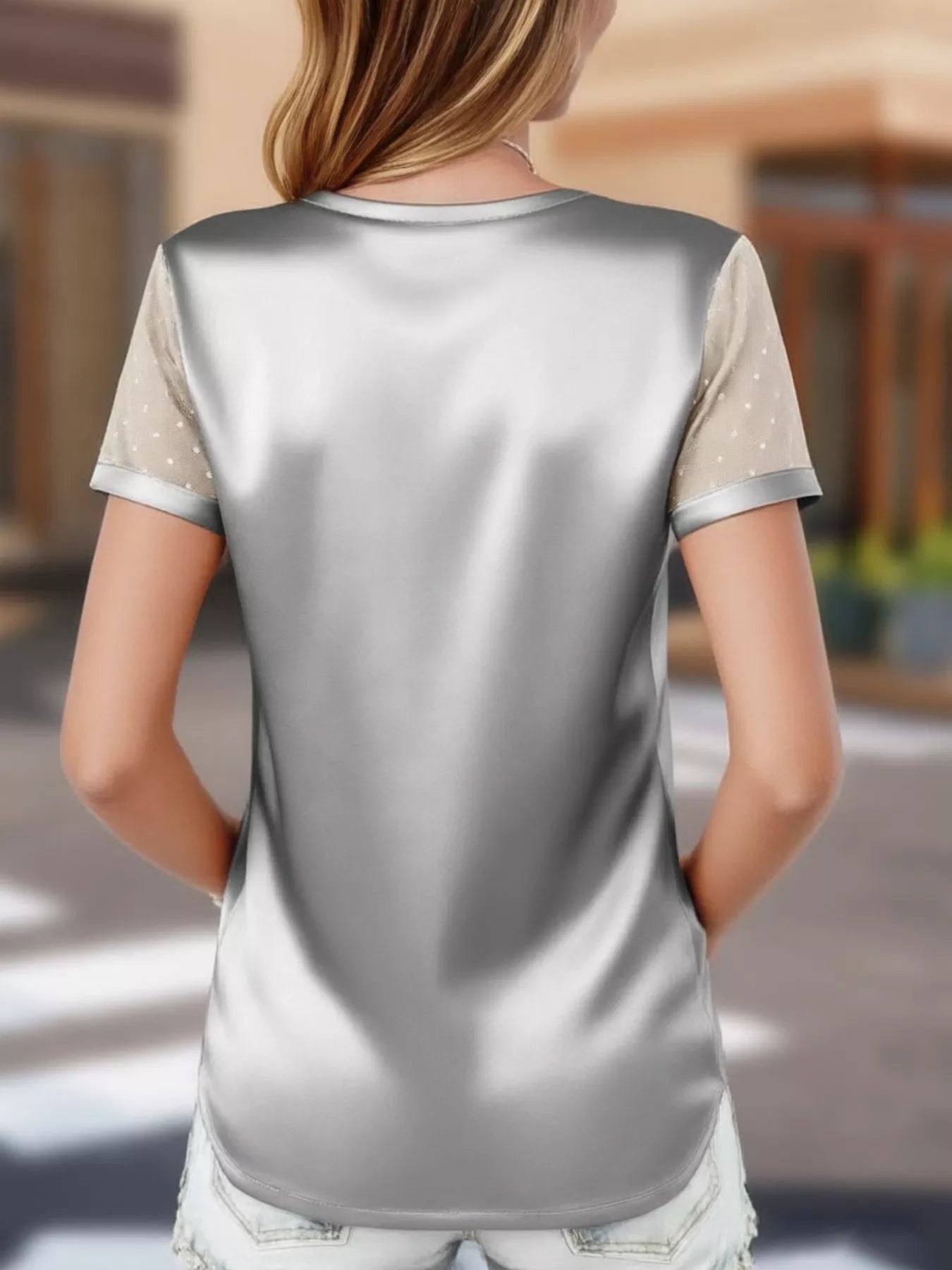 Person wearing a silver and beige top with a blurred background