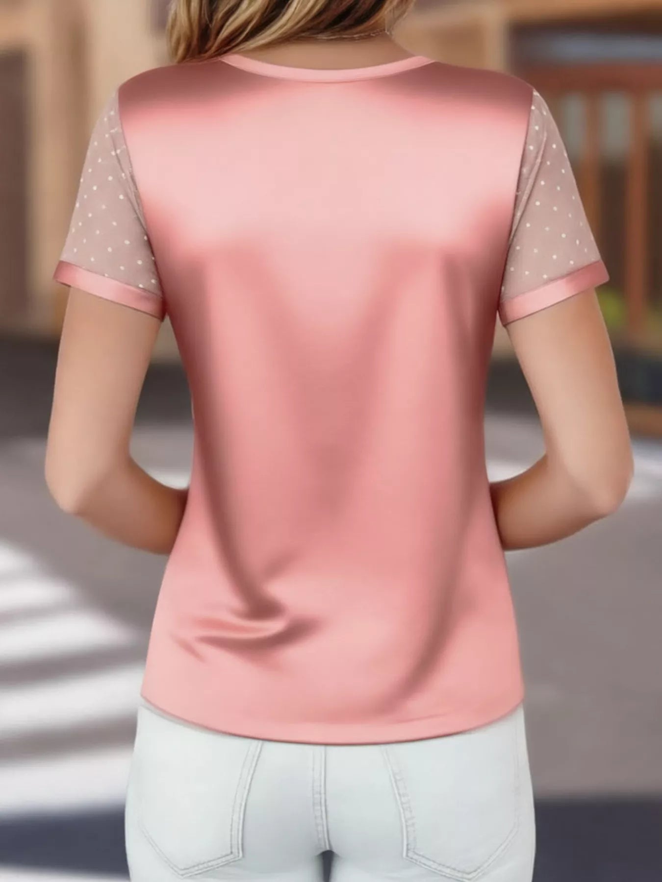 Pink short-sleeve top with polka dot sleeves worn by a person, blurred background