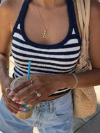 Person wearing a striped tank top and holding a drink with a straw.