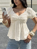 Woman wearing a white textured blouse and blue jeans, holding a phone.