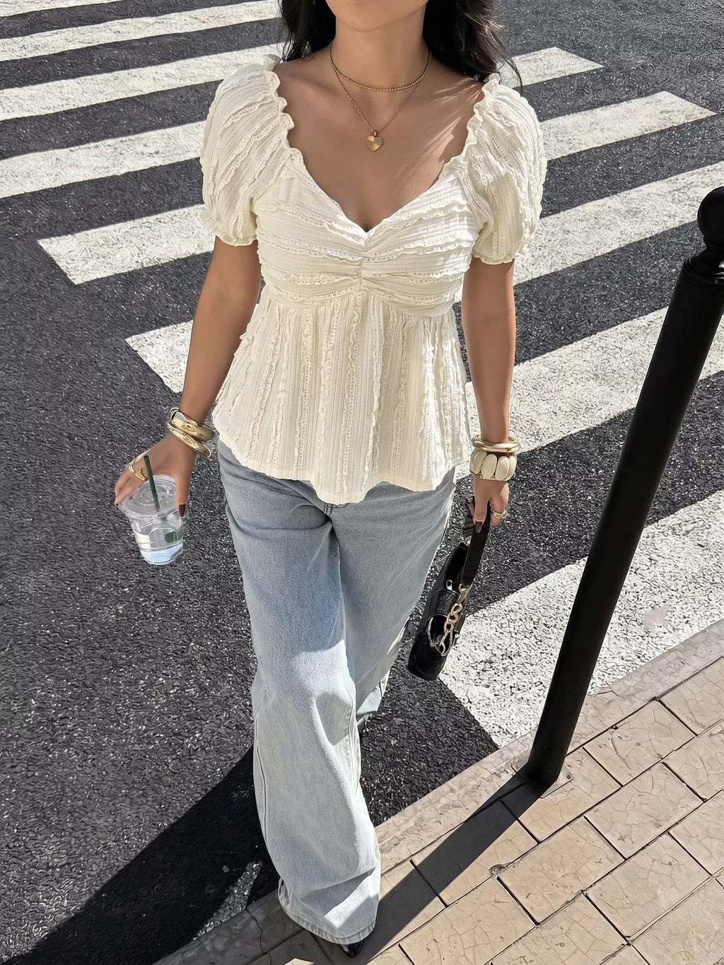 Person wearing a white blouse and light blue jeans on a crosswalk