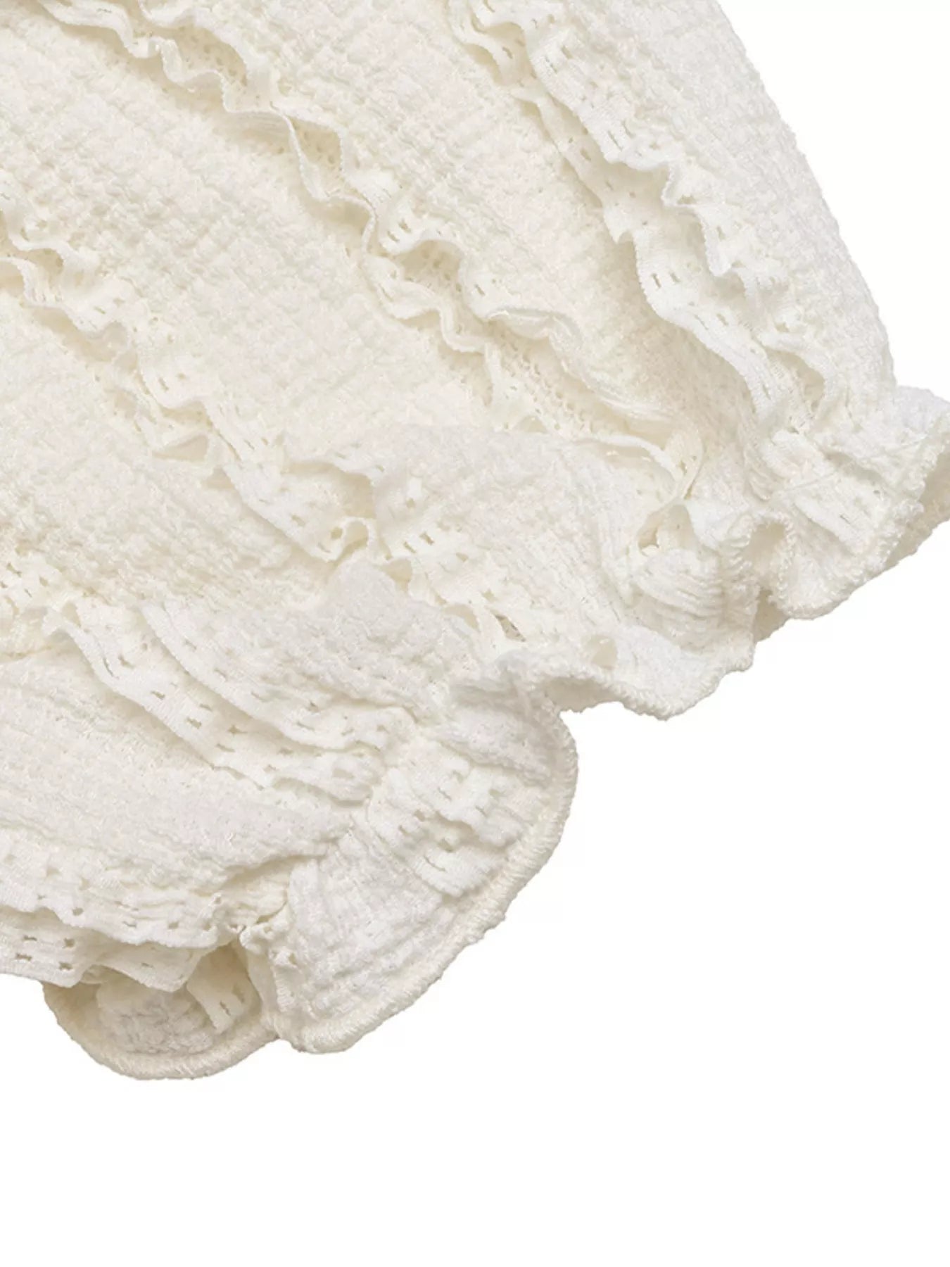 Close-up of a white lace fabric with ruffled edges on a white background