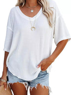 Woman wearing a white textured top and denim shorts with a plain background