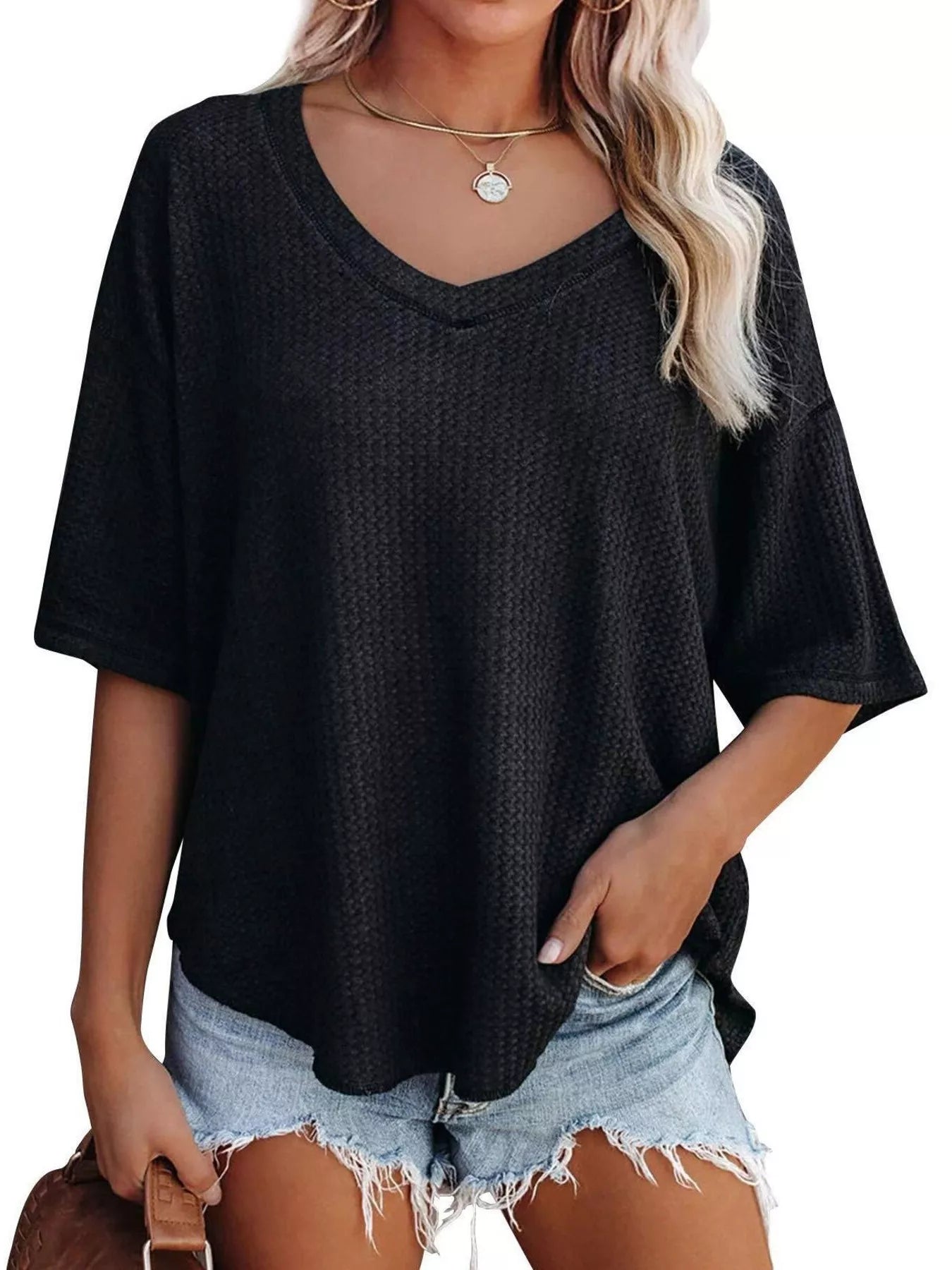 Person wearing a black oversized t-shirt and denim shorts on a white background