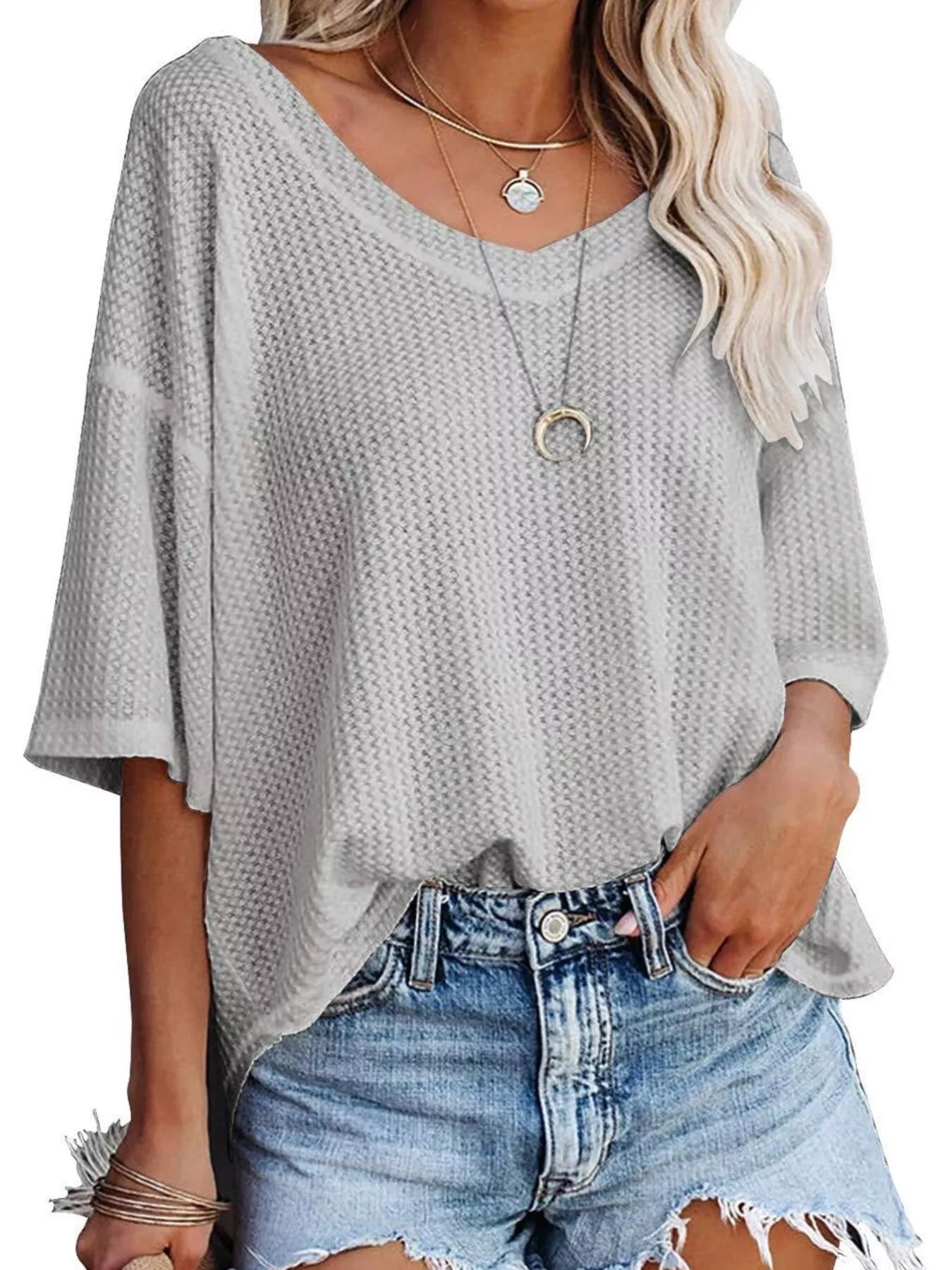 Woman wearing a gray textured blouse and denim shorts on a white background