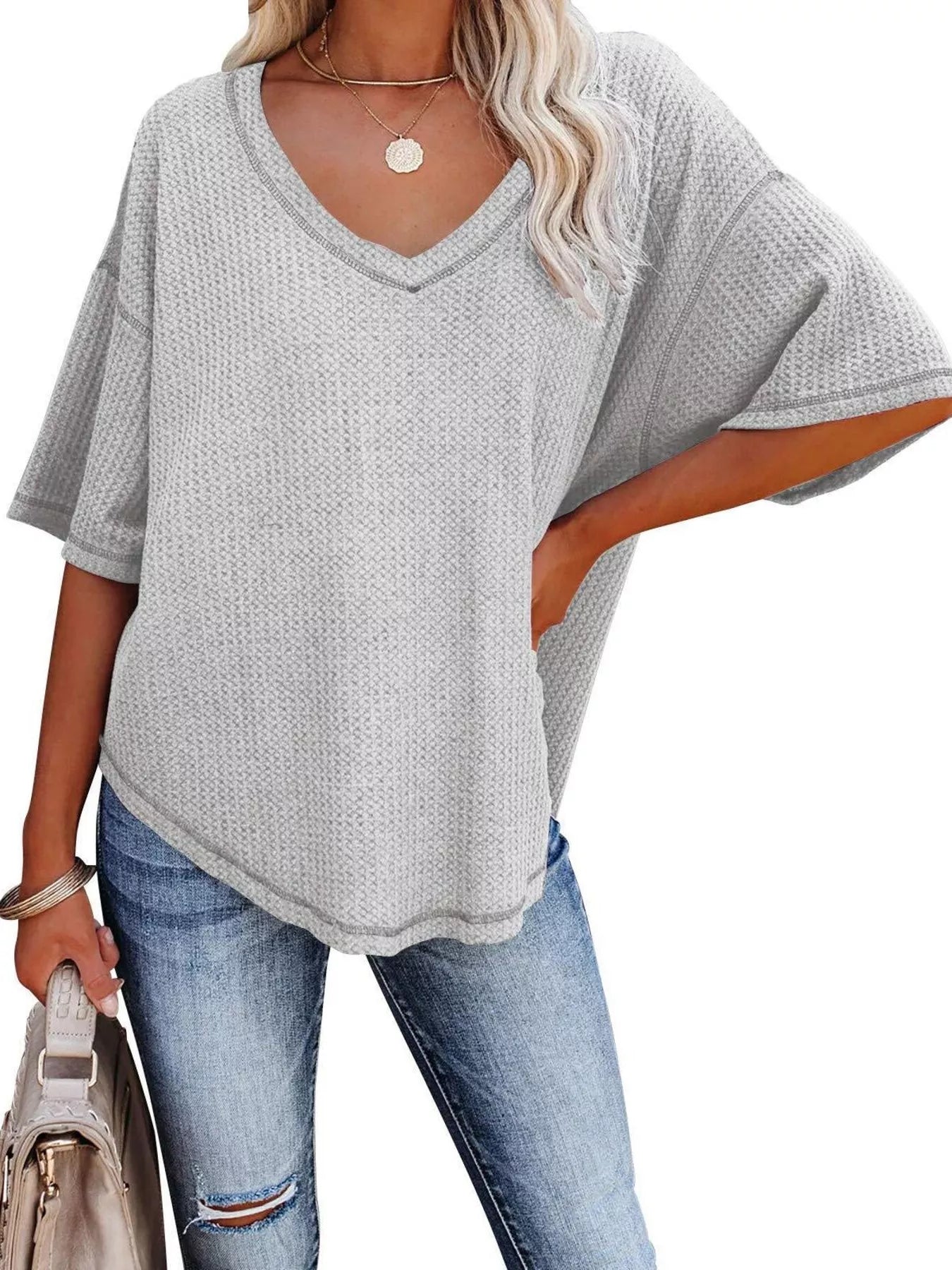 Woman wearing a gray oversized t-shirt and blue jeans on a white background
