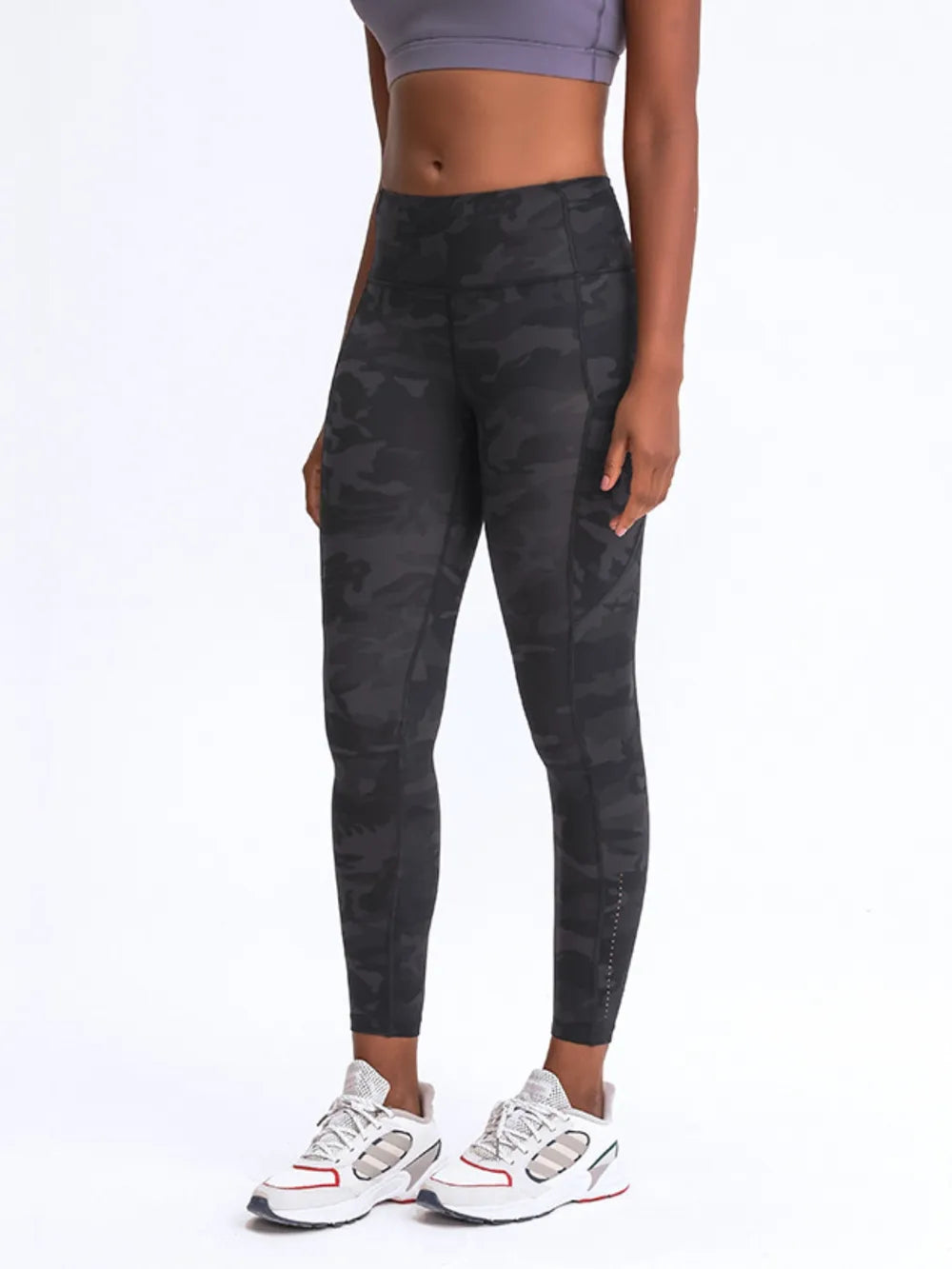 Person wearing black camouflage leggings on a white background