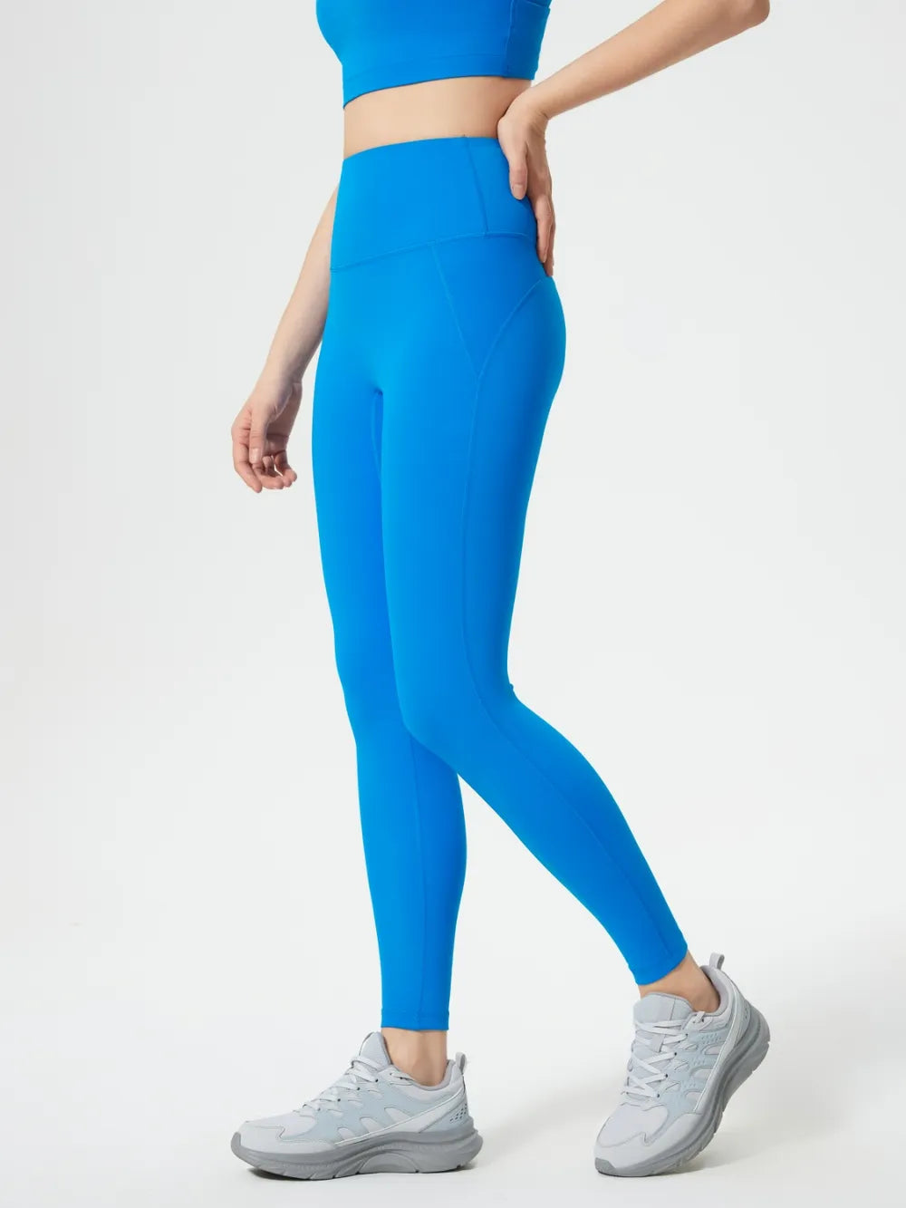 Person wearing bright blue leggings and a matching top on a white background