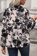 Person wearing a floral patterned blouse with black flowers on a light pink background.