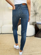 Person wearing blue jeans and white sneakers in a living room setting