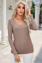 Woman wearing a brown ribbed long-sleeve top with a pocket, standing outdoors.
