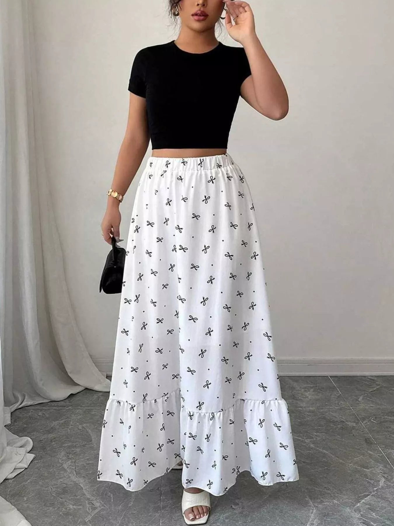 Woman wearing a black crop top and white skirt with butterfly pattern indoors.