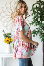 Woman wearing a floral dress standing in a room with decorative plants and a sunflower.