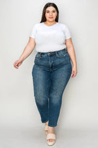 Woman wearing a white t-shirt and blue jeans on a plain background