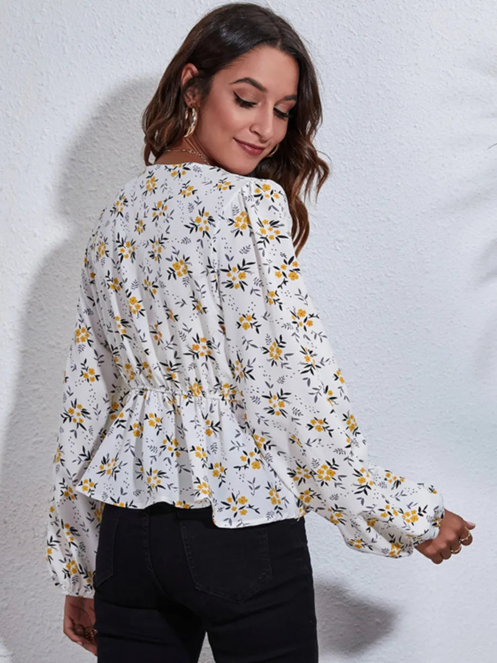 Woman wearing a floral blouse with long sleeves against a plain background