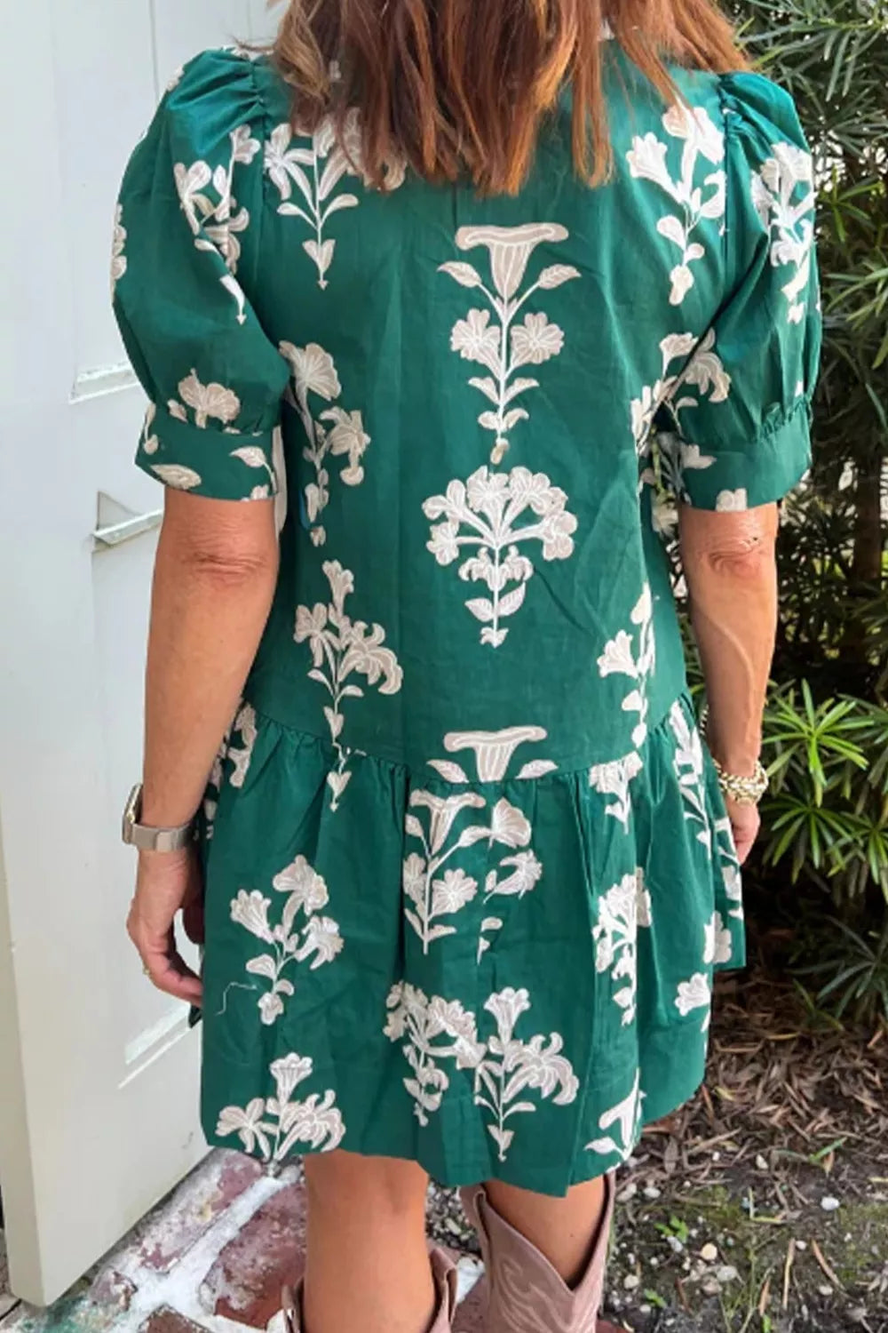 Person wearing a green dress with white floral patterns outdoors.