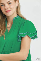 Woman wearing a green dress with scalloped sleeves on a white background