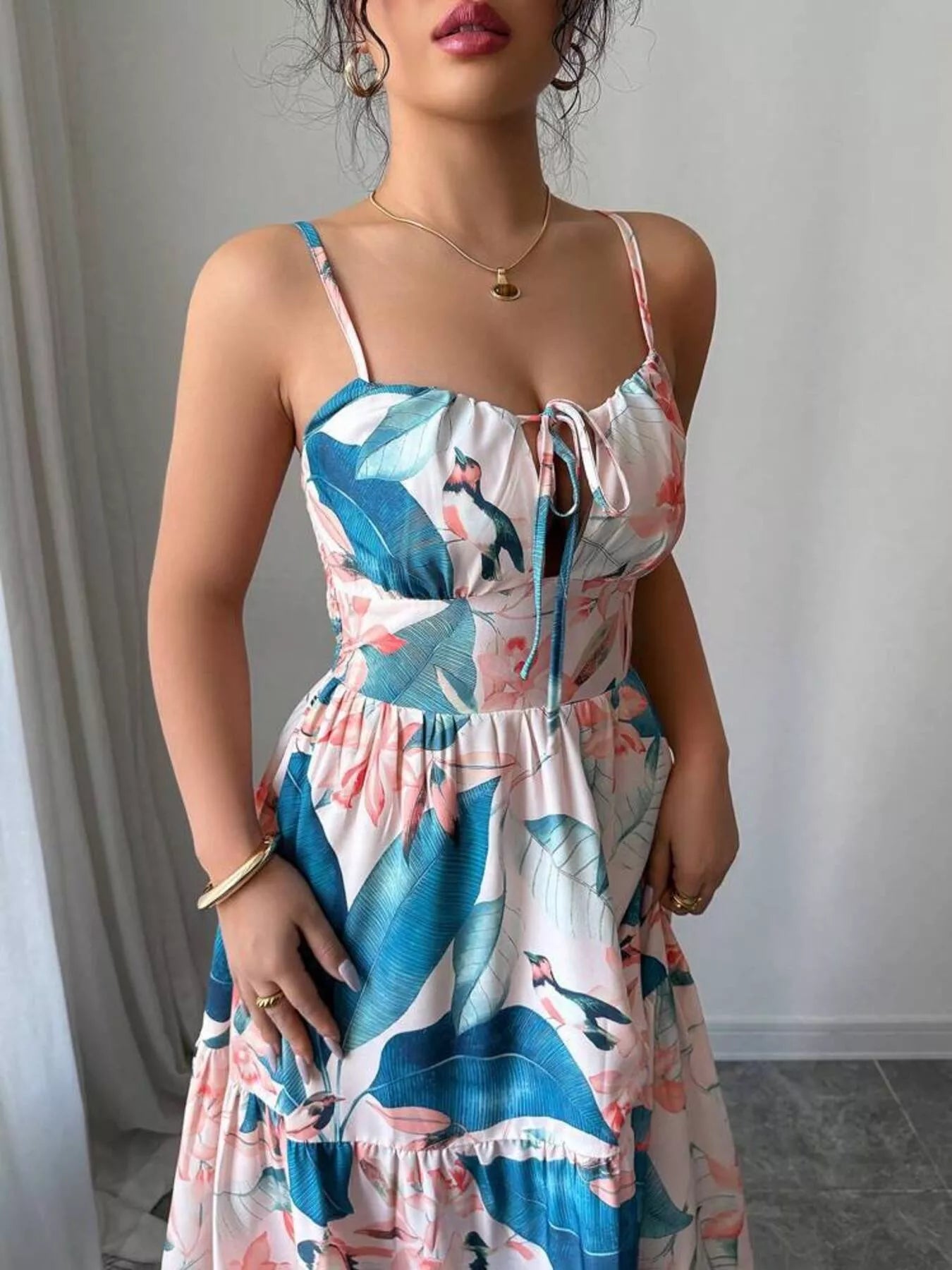 Woman wearing a floral dress with blue and pink patterns against a neutral background