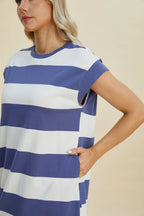Woman wearing a blue and white striped dress against a beige background