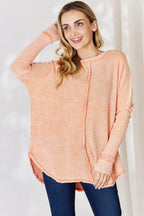Woman wearing a peach-colored long-sleeve top against a white background