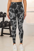 Person wearing gray and black patterned leggings in a gym setting with weights in the background.