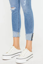 Blue distressed jeans and white sneakers on a light gray background