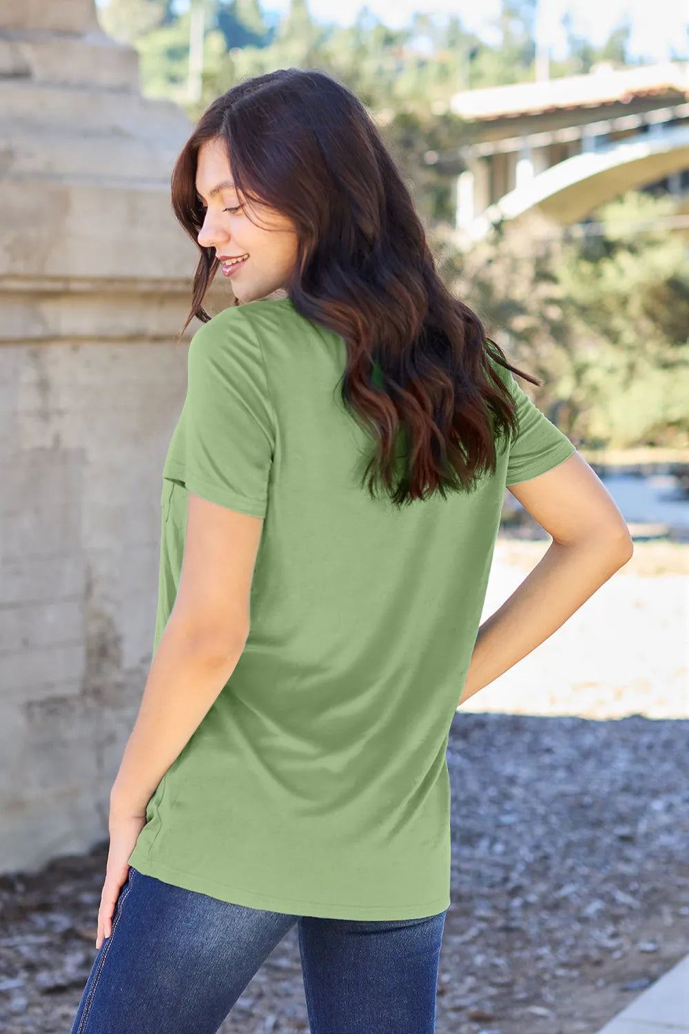 Woman wearing a green t-shirt with a blurred outdoor background