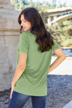 Woman wearing a green t-shirt with a blurred outdoor background