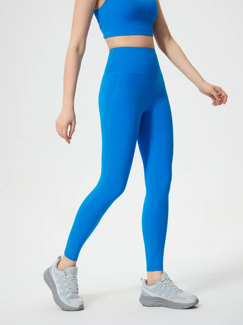 Person wearing blue athletic leggings and top on a white background