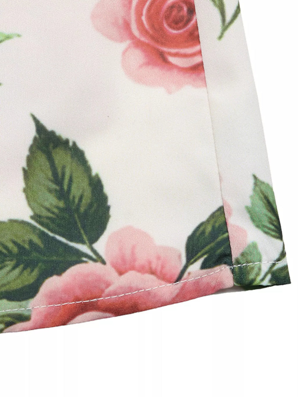 Close-up of floral fabric with pink roses and green leaves on a white background