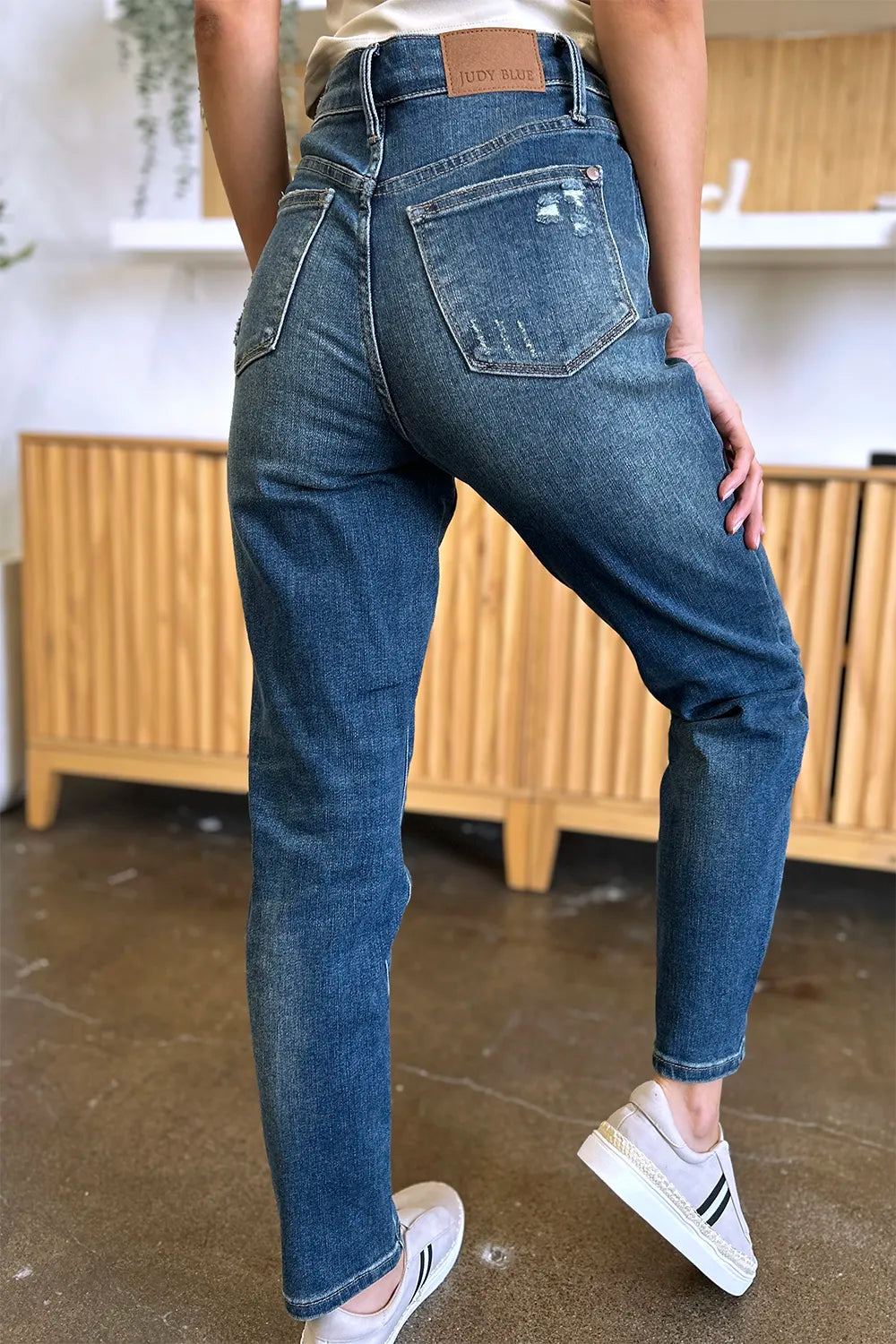 Person wearing blue jeans and white sneakers in a casual setting