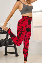 Person wearing red and black patterned leggings and gray sports bra in a gym setting.