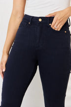 Navy blue jeans worn by a person on a white background